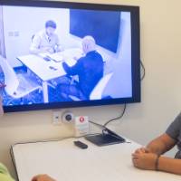 Two people sitting at table looking at video playing on TV screen